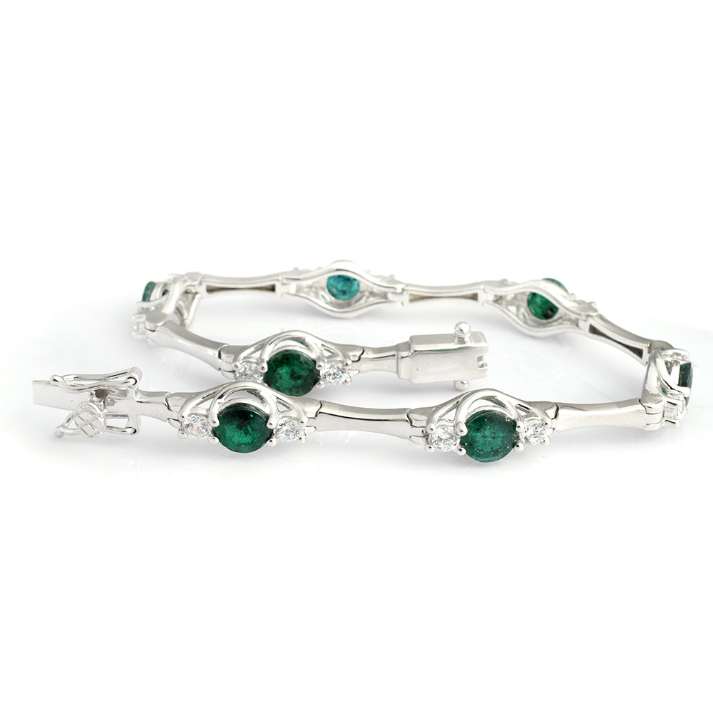 A silver-toned tennis bracelet featuring five round-cut green emeralds and small clear accent stones, displayed on a clean white background.