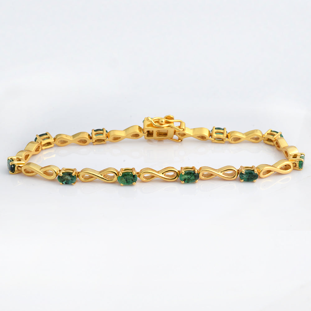 A yellow gold tennis bracelet featuring repeating links with square-cut green emerald-cut gemstones, displayed on a clean white background.