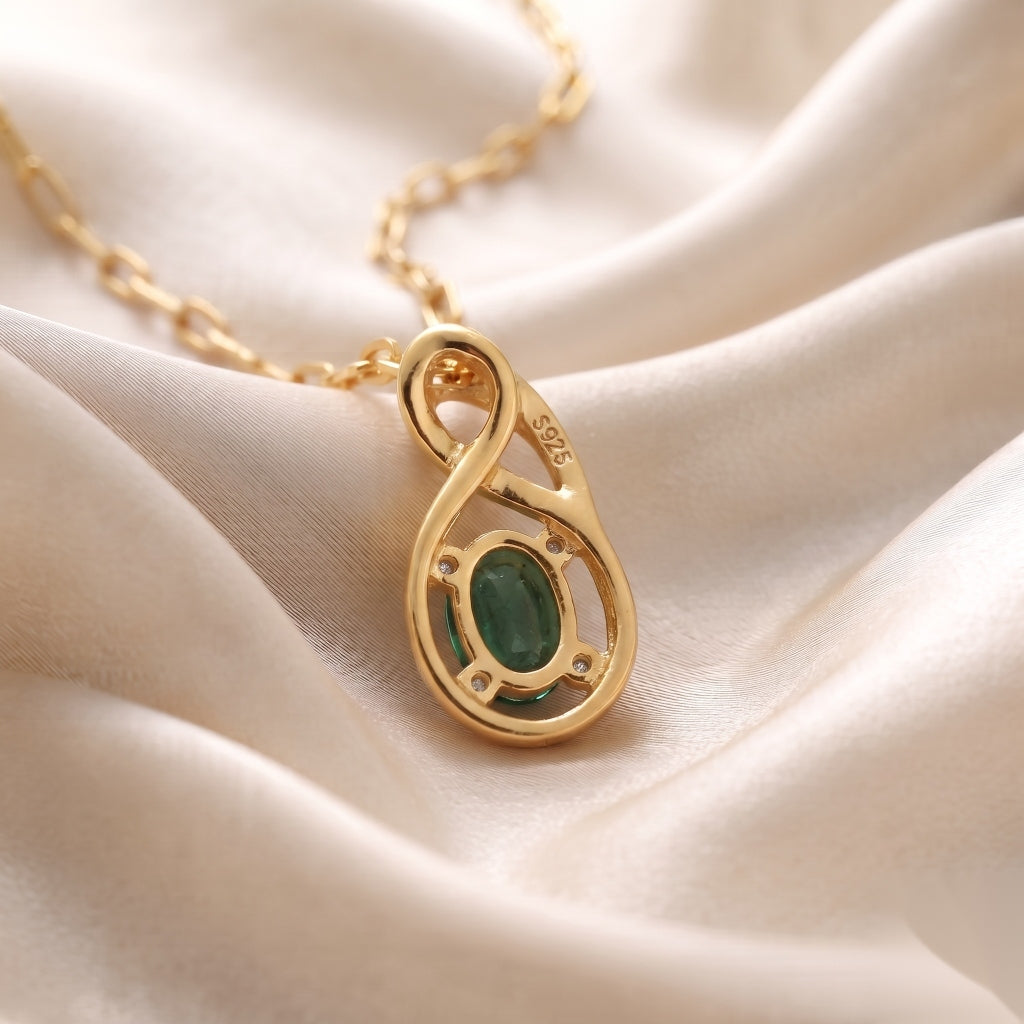 Ganpati natural emerald CZ infinity pendant with oval green gemstone on gold vermeil 925 silver chain, back view with silk background.
