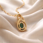 Ganpati natural emerald CZ infinity pendant with oval green gemstone on gold vermeil 925 silver chain, back view with silk background.