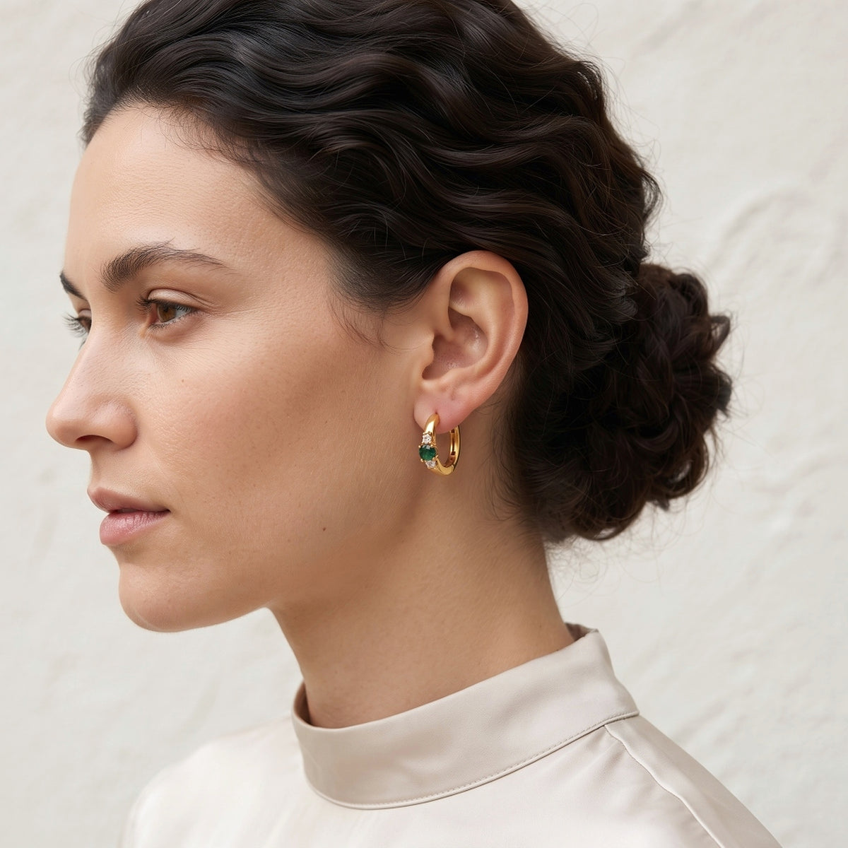 Ganpati gold vermeil silver emerald CZ trilogy huggie earrings featuring bold green gemstones and large three-stone hoop design.