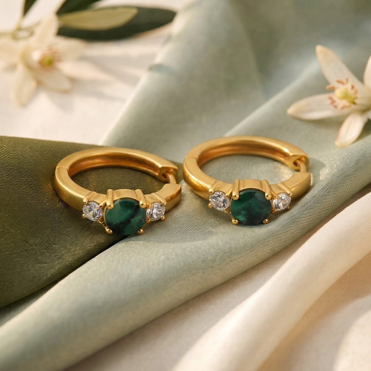 Ganpati gold vermeil silver emerald trilogy huggie earrings with bold green gemstones, featuring large three-stone emerald designs.