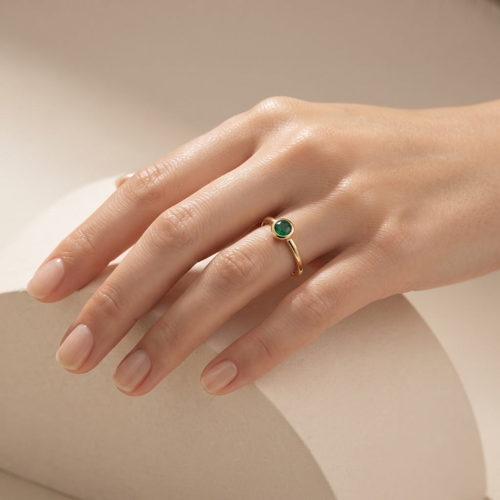 Model wearing Ganpati natural emerald bezel ring in gold vermeil with 925 silver, featuring a round emerald solitaire and minimalist design.