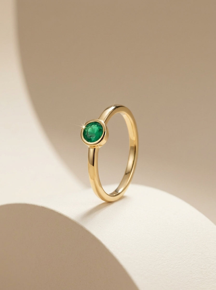 Ganpati gold vermeil silver ring with round emerald solitaire, showcasing a dainty green gemstone in a minimalist bezel setting.